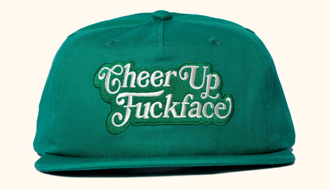 Green snapback cap with cream text 'CheerUp Fuckface' embroidered on the front