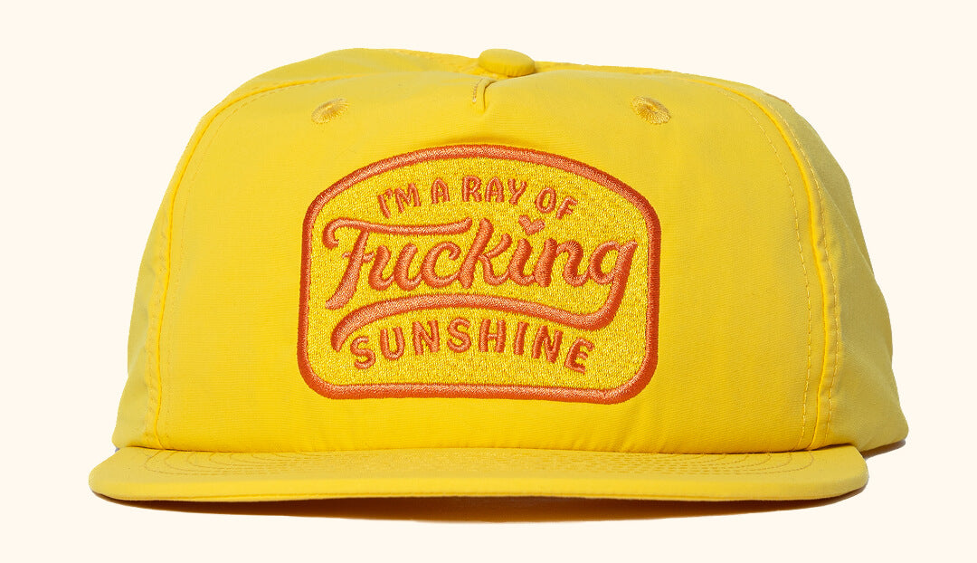 A yellow nylon snapback cap with the text 'I'm A Ray of Sunshine' embroidered on the front.