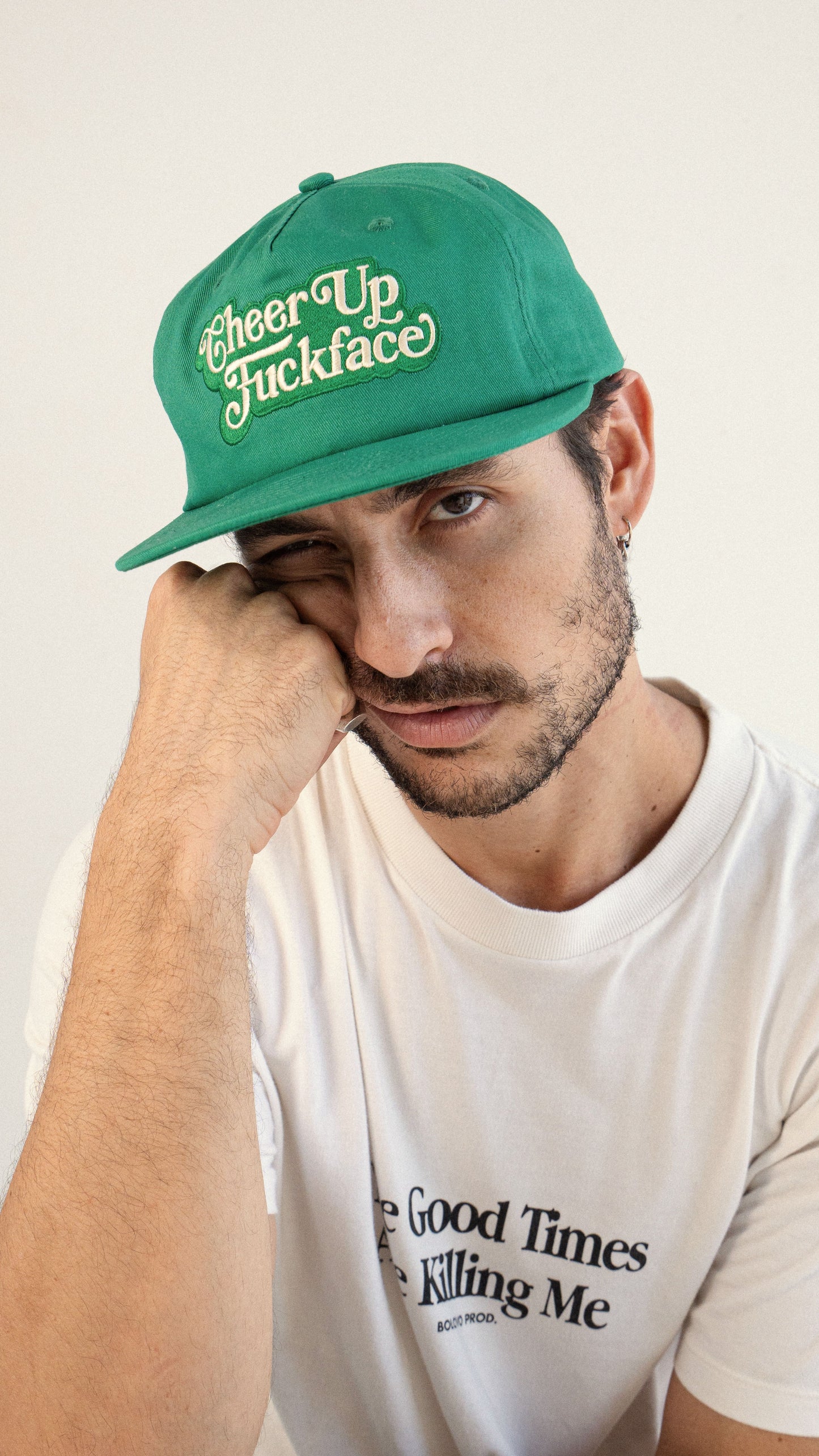 Man wearing a green cap with text, against a plain background