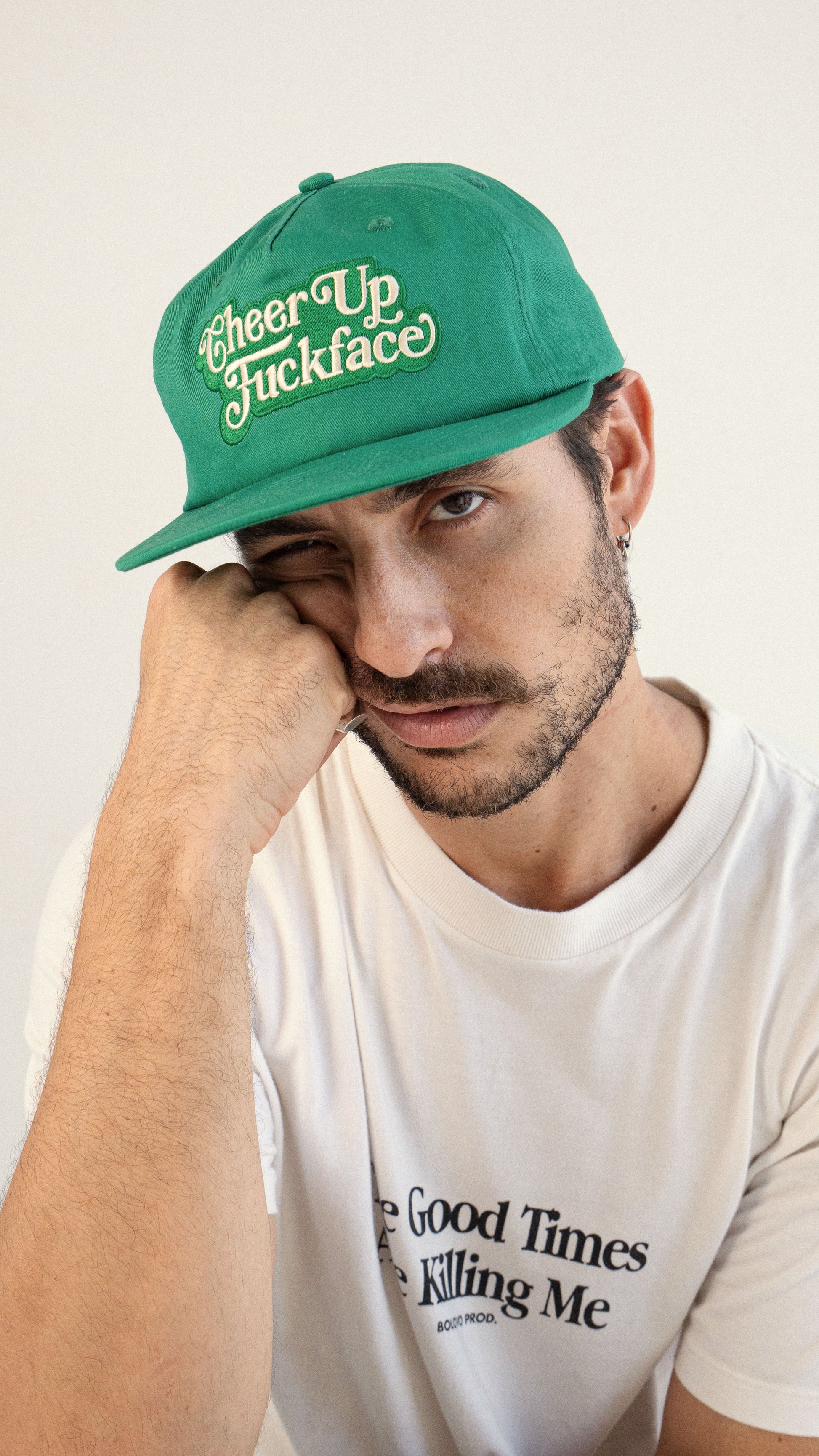 Man wearing a green cap with text, against a plain background